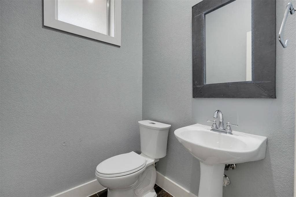4830 Cedar Springs Road, #30, Dallas, TX 75219 Pedestal sink with chrome faucet, white toilet, and dark framed mirror