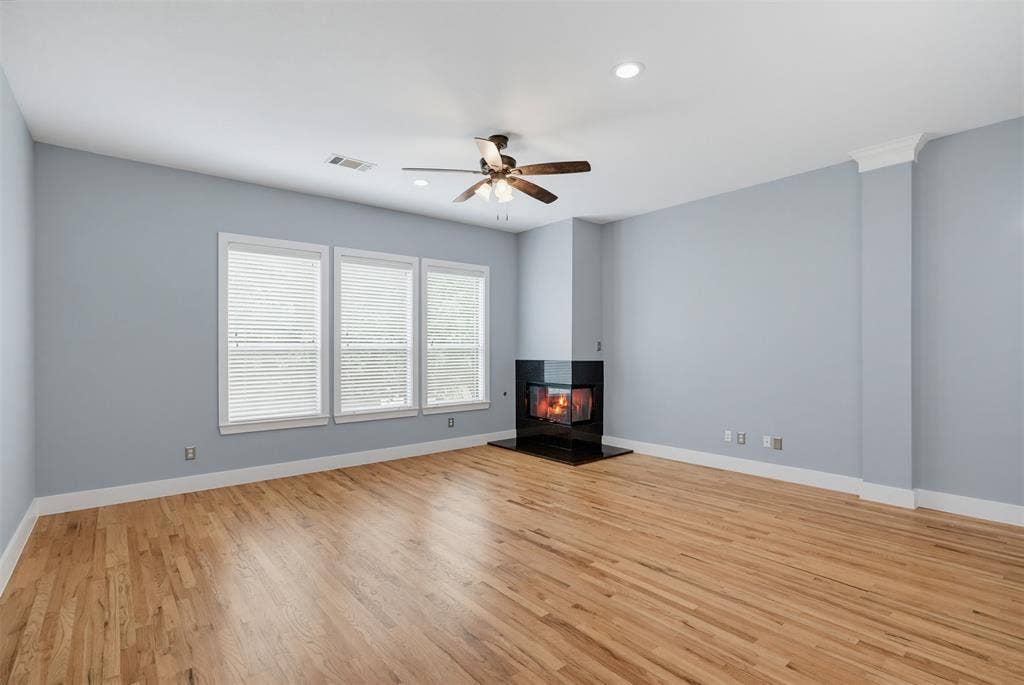 4830 Cedar Springs Road, #30, Dallas, TX 75219 Living area featuring a corner fireplace with a dark surround, light wood-finish flooring, three windows with blinds, a ceiling fan, and recessed lighting