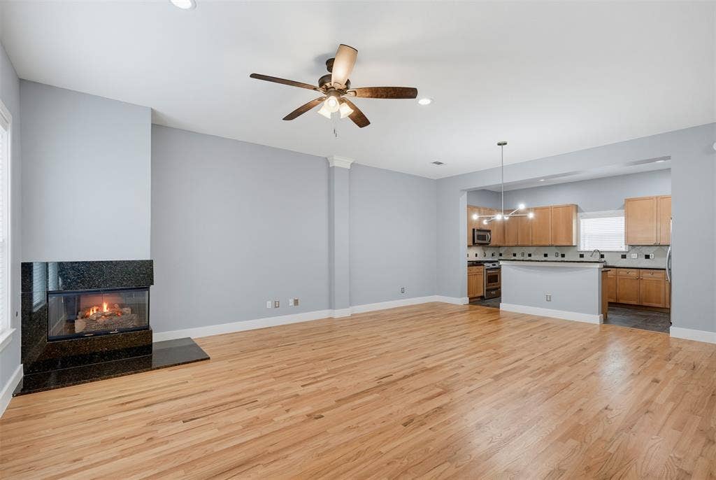 4830 Cedar Springs Road, #30, Dallas, TX 75219 Open-concept living area featuring wood-finish flooring, a contemporary fireplace with a dark stone surround, and recessed lighting