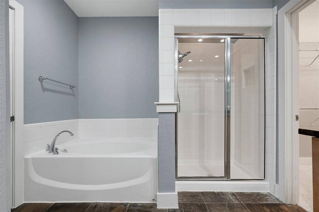 4830 Cedar Springs Road, #30, Dallas, TX 75219 Bathroom featuring a soaking tub with chrome fixtures, a tiled shower with a glass enclosure, wood-finish flooring, and light-toned wall paint