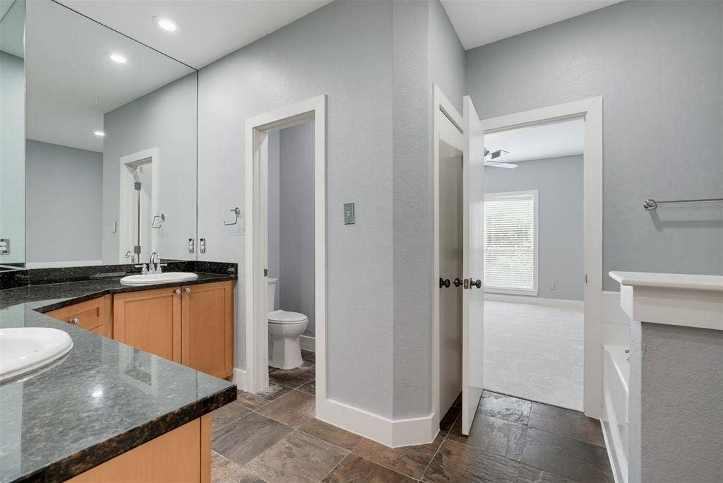 4830 Cedar Springs Road, #30, Dallas, TX 75219 Bathroom featuring a double vanity with stone countertops, wood cabinetry, and extensive wall mirror