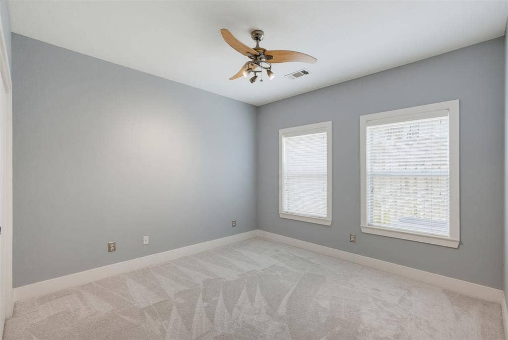 4830 Cedar Springs Road, #30, Dallas, TX 75219 Carpeted room with light grey walls, two windows featuring white blinds, and a ceiling fan with integrated lighting