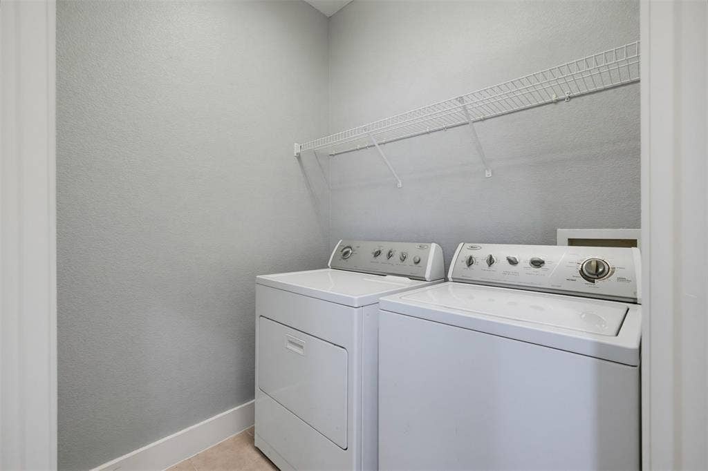 4830 Cedar Springs Road, #30, Dallas, TX 75219 Dedicated laundry area featuring a white washer and dryer set, overhead wire shelving, light gray wall finish, and neutral flooring