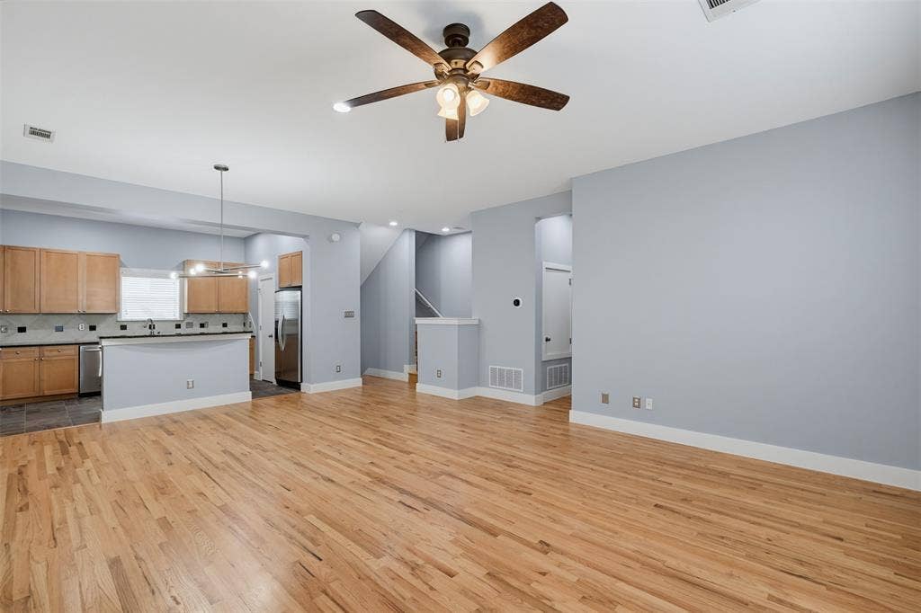 4830 Cedar Springs Road, #30, Dallas, TX 75219 Living area featuring wood-finish flooring, a contemporary fireplace with a black stone surround and hearth, a wood mantel, recessed lighting, and a ceiling fan
