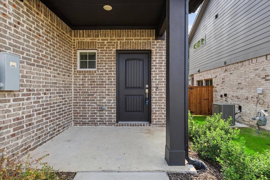 202 Griffith Drive, #16, Princeton, TX 75407 Welcoming covered entryway featuring substantial brick exterior with contrasting dark panel door, recessed ceiling lighting, and concrete flooring