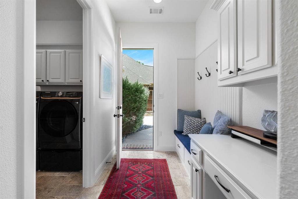 Mudroom with built in desk and adjacent laundry room