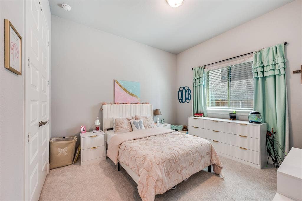 2703 Trinity Ridge Street, Mansfield, TX 76063 Carpeted bedroom featuring a window with horizontal blinds, a ceiling-mounted light fixture, and a solid door with panel detailing