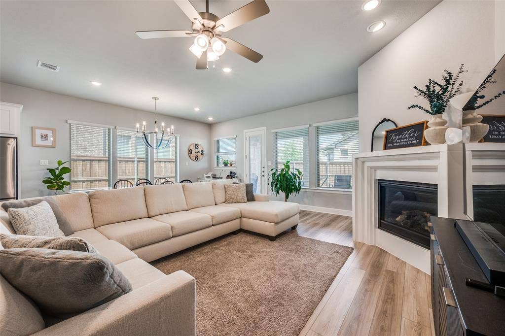2703 Trinity Ridge Street, Mansfield, TX 76063 Living area featuring a corner fireplace with a white mantel, wood-finish flooring, and recessed lighting