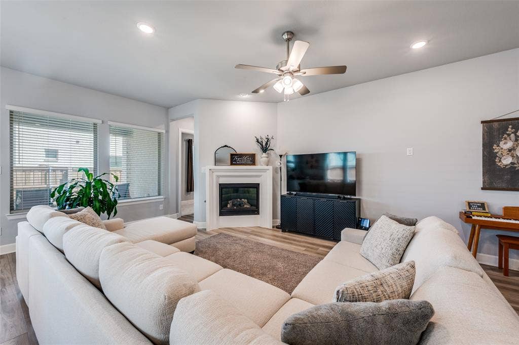 2703 Trinity Ridge Street, Mansfield, TX 76063 Living room featuring a corner fireplace with a white mantel, wood-finish flooring, recessed lighting, and a ceiling fan