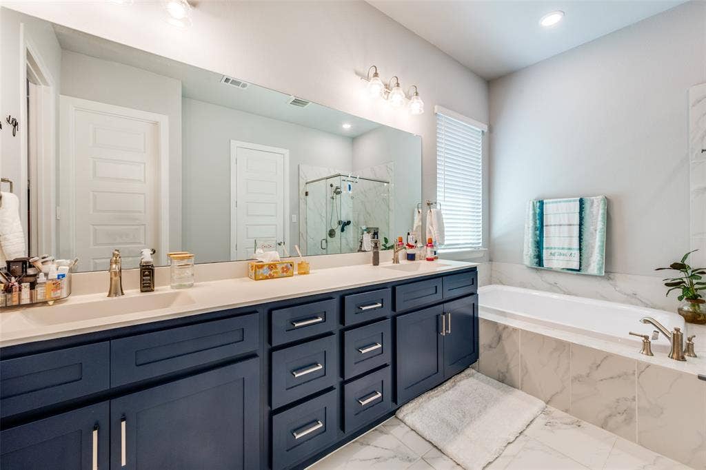 2703 Trinity Ridge Street, Mansfield, TX 76063 Dual vanity featuring navy cabinetry with brushed nickel hardware, white countertops, and integrated sinks
