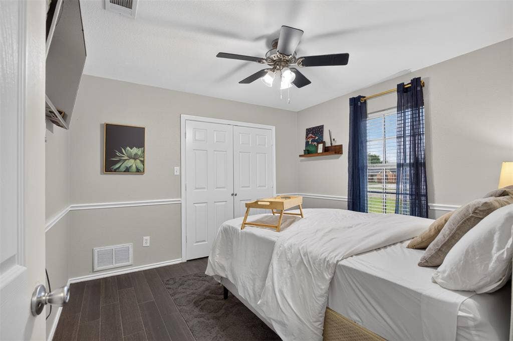 Bedroom featuring wood-finish flooring, white trim, a double-door closet, and a ceiling fan with integrated lighting