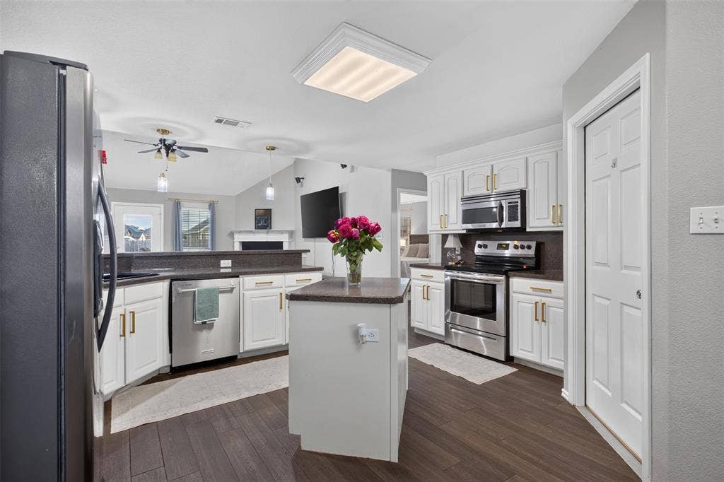 Modern kitchen featuring white cabinetry, dark countertops, and stainless steel appliances