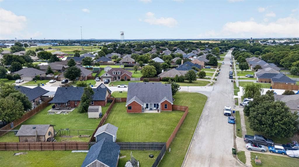Residential neighborhood featuring an array of single-story homes with dark roofs and mature trees lining the streets