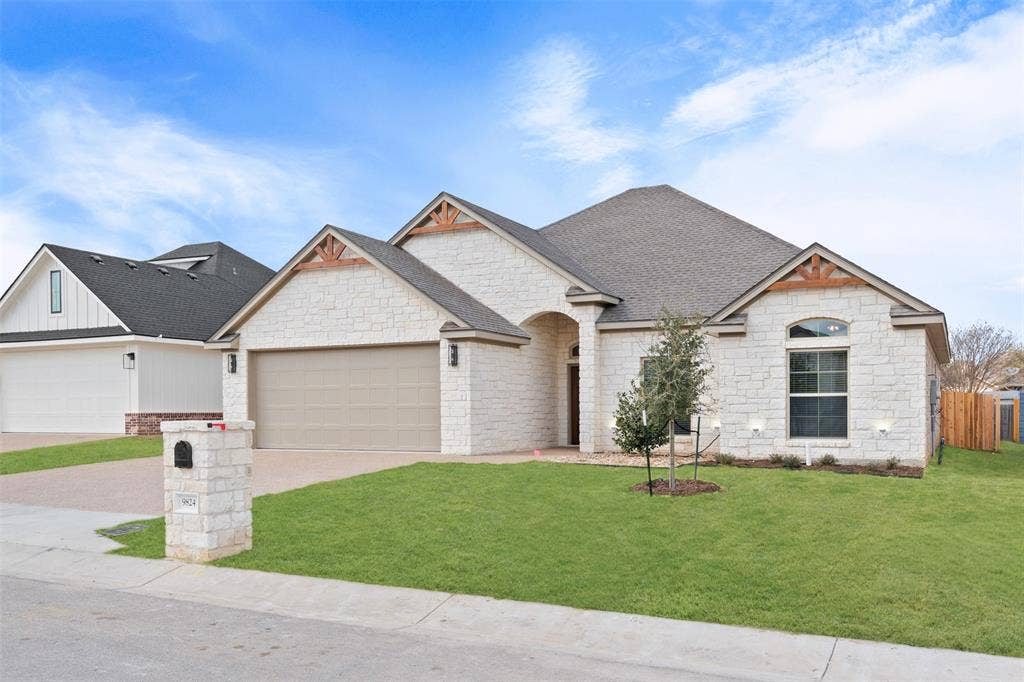 9824 Durango Trail, Waco, TX 76712 Stone exterior featuring a two-car garage, arched entry, and gabled rooflines with exposed wood accents