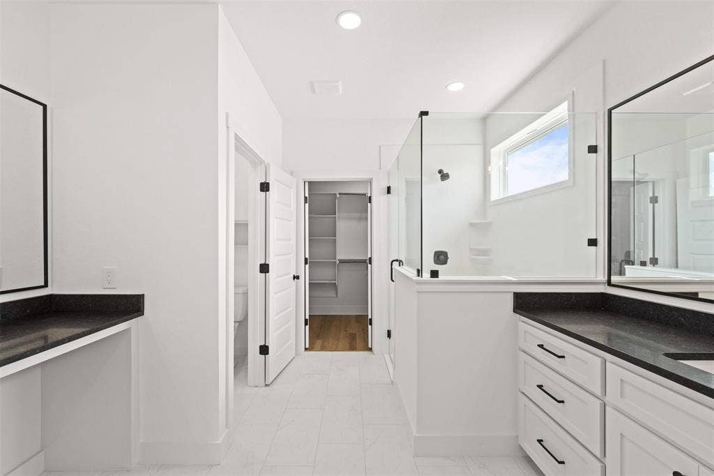 9820 Durango Trail, Waco, TX 76712 Contemporary bathroom featuring dual vanities with dark countertops, a glass-enclosed shower, a privacy window, and tile flooring