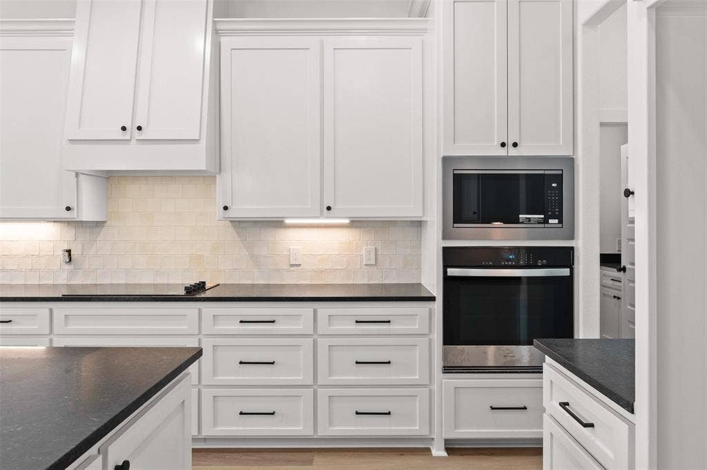 9820 Durango Trail, Waco, TX 76712 Contemporary kitchen featuring white shaker cabinetry, dark countertops, a built-in microwave, a wall oven, and a tiled backsplash