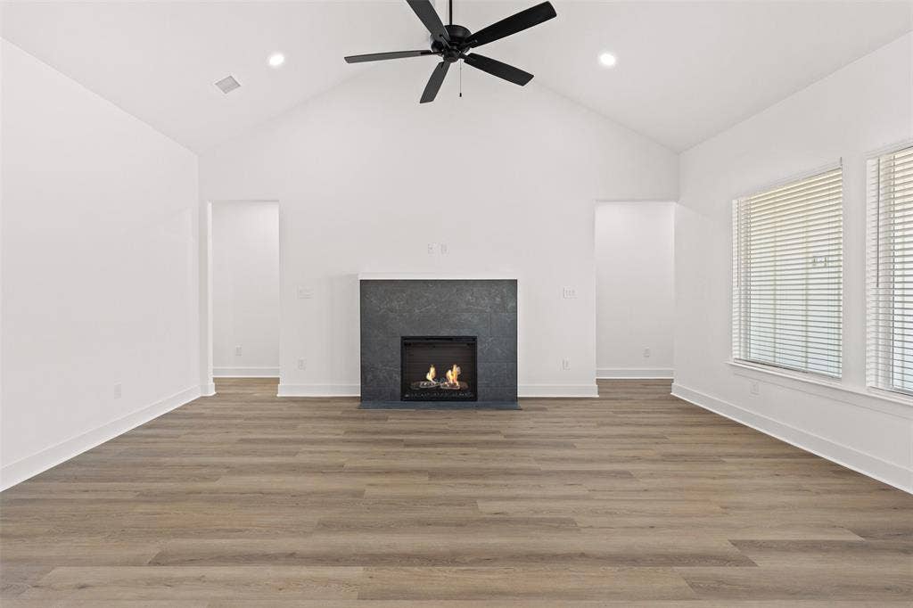 9820 Durango Trail, Waco, TX 76712 Spacious room featuring vaulted ceilings, wood-finish flooring, and a modern fireplace with a dark stone-look surround