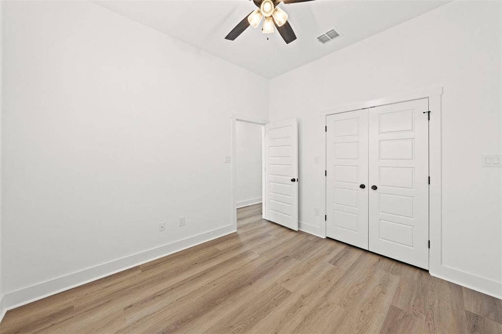 9820 Durango Trail, Waco, TX 76712 Bright room featuring wood-finish flooring, white baseboards, a ceiling fan with light fixture, and a double-door closet with black hardware