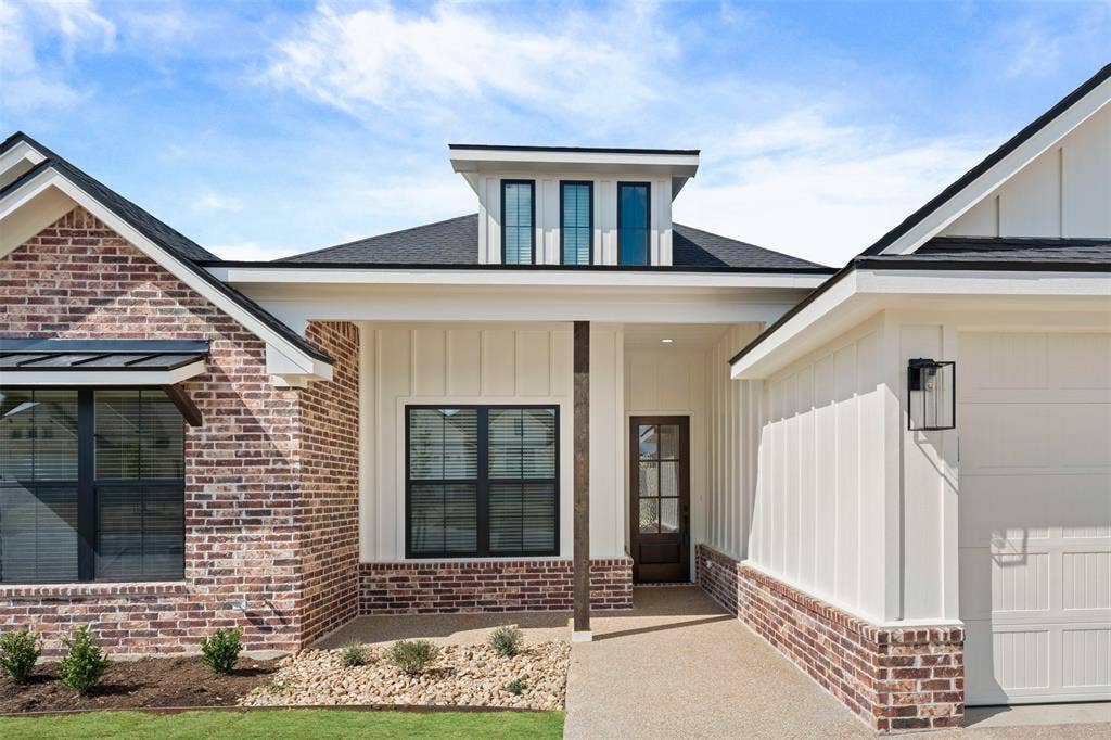 9820 Durango Trail, Waco, TX 76712 Modern farmhouse exterior featuring a prominent gabled roofline, brick and vertical board-and-batten siding, black-framed windows, and a covered entry with a dark wood-paneled door