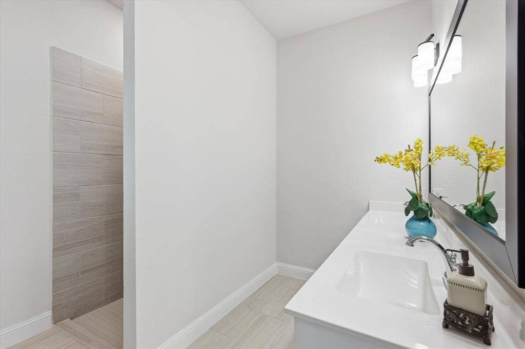 4017 Alpine Street, Midlothian, TX 76065 Bathroom featuring a single vanity with an integrated sink, polished chrome faucet, and expansive wall-mounted mirror with a black frame