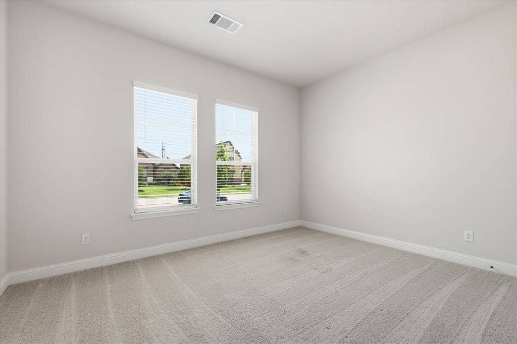 4017 Alpine Street, Midlothian, TX 76065 Light-filled room featuring two windows with blinds, neutral carpeting, white baseboards, and a ceiling-mounted air vent