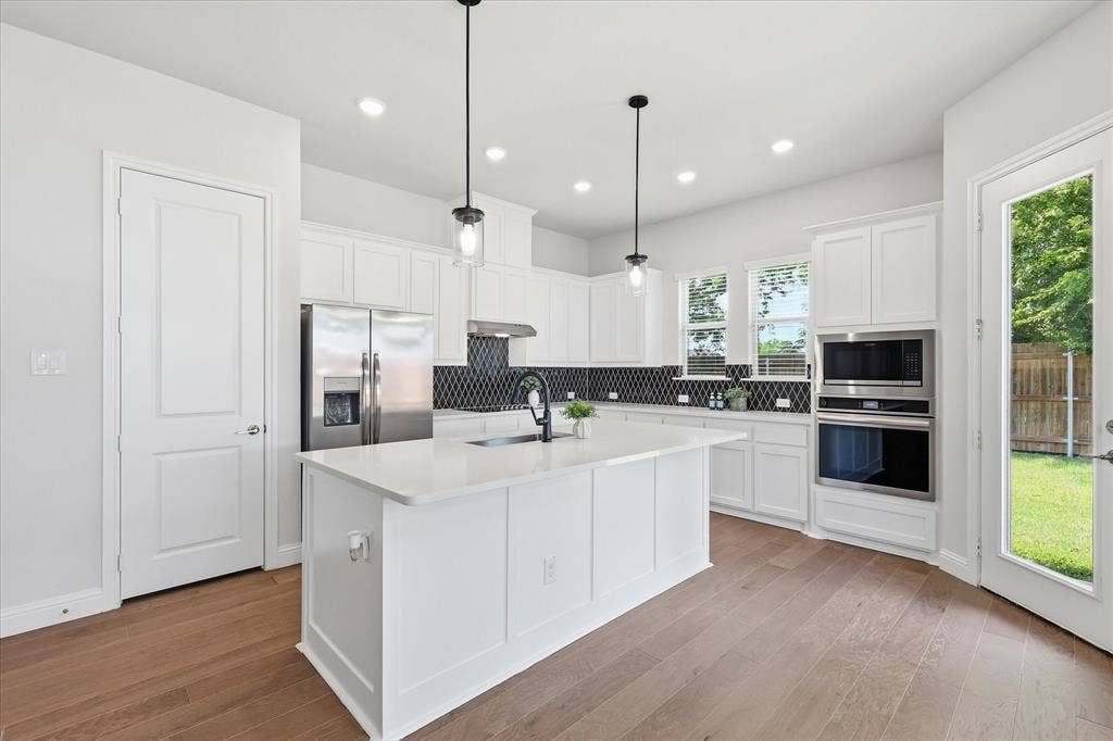 4017 Alpine Street, Midlothian, TX 76065 Modern kitchen featuring a large central island, white cabinetry, and wood-finish flooring