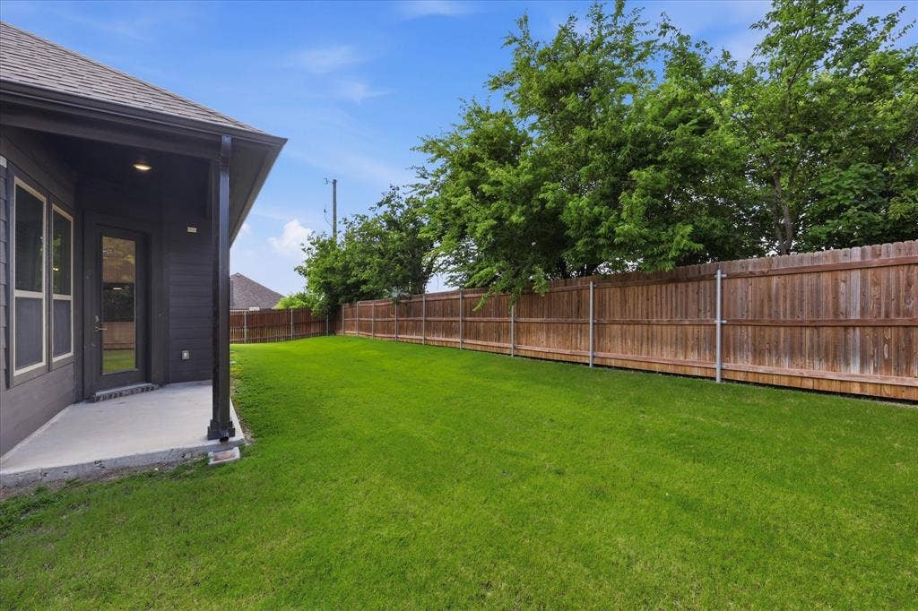 4017 Alpine Street, Midlothian, TX 76065 Spacious backyard featuring an expansive manicured lawn, a wood privacy fence, and mature trees