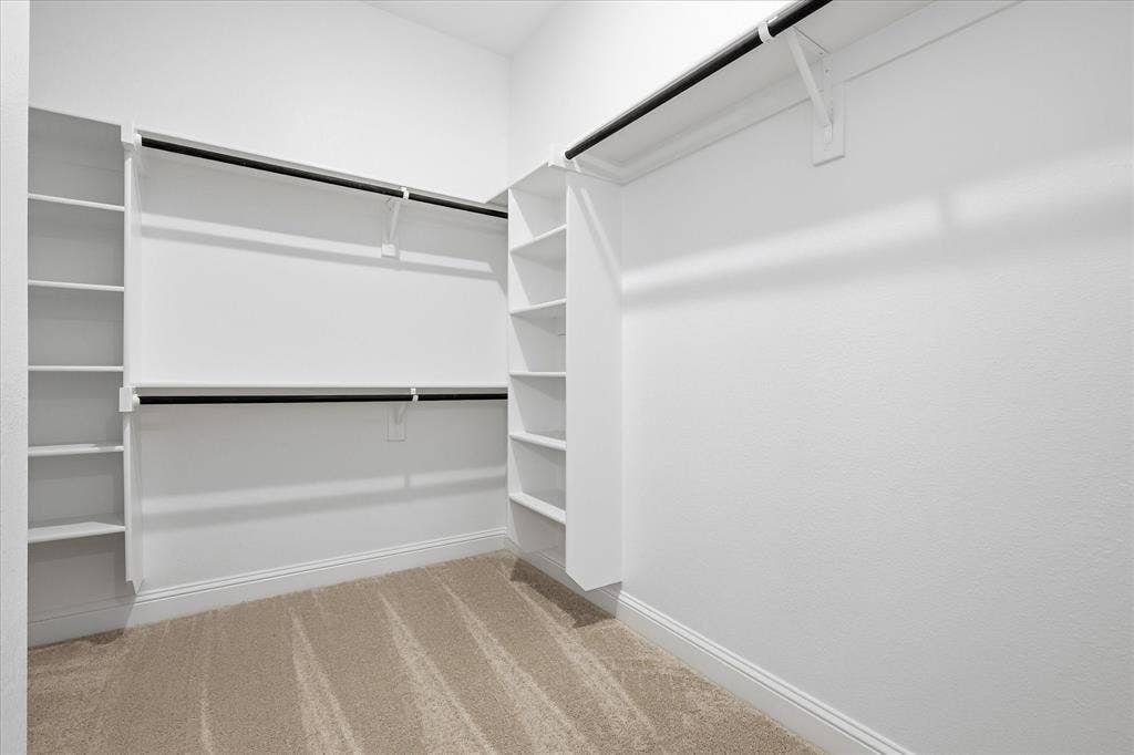 4017 Alpine Street, Midlothian, TX 76065 Walk-in closet featuring built-in shelving, dual hanging rods, light beige carpeting, white walls, and white baseboards