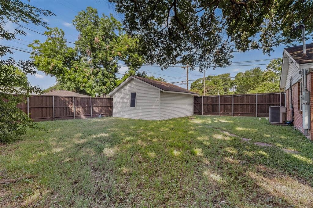 405 Easton Road, Dallas, TX 75218 Spacious backyard featuring a detached outbuilding, wood privacy fencing, and brick exterior siding on the main dwelling
