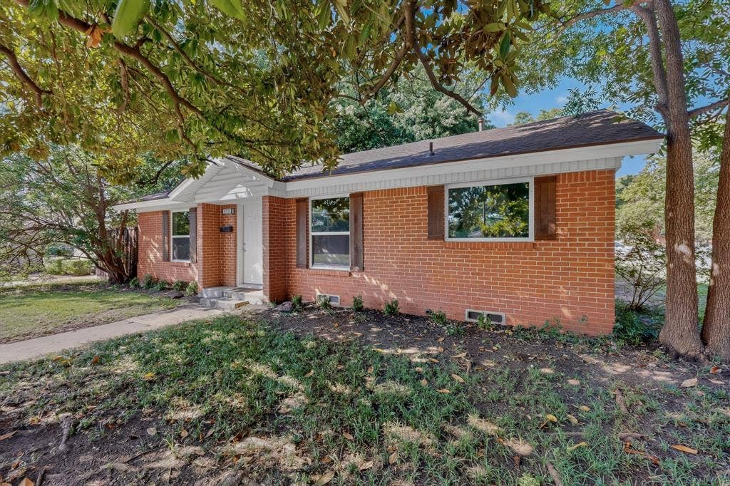 405 Easton Road, Dallas, TX 75218 Brick exterior residence featuring a white front door, white trim, wood-finish shutters, and a sloped roofline