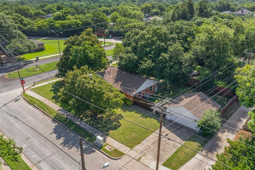 405 Easton Road, Dallas, TX 75218 Aerial perspective showcasing a property with a manicured lawn, a detached garage, and mature trees providing natural shading