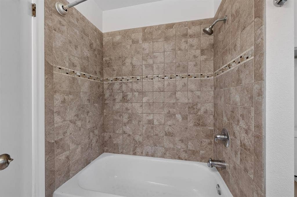 405 Easton Road, Dallas, TX 75218 Bathtub with full-height tile surround featuring a decorative mosaic accent band