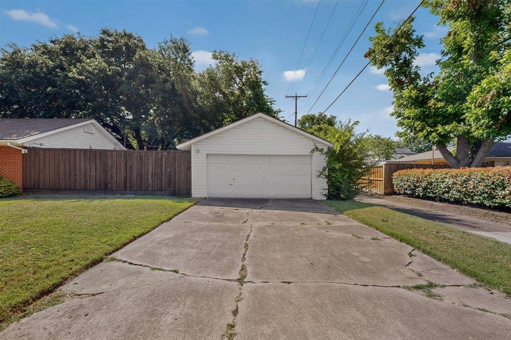 405 Easton Road, Dallas, TX 75218 Detached white siding garage with a single garage door, concrete driveway, and surrounding green lawn