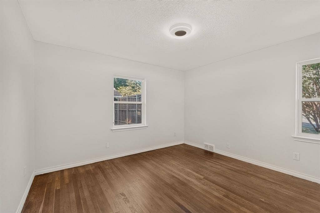 405 Easton Road, Dallas, TX 75218 Bright interior room featuring wood-finish flooring, white baseboards, and neutral wall paint