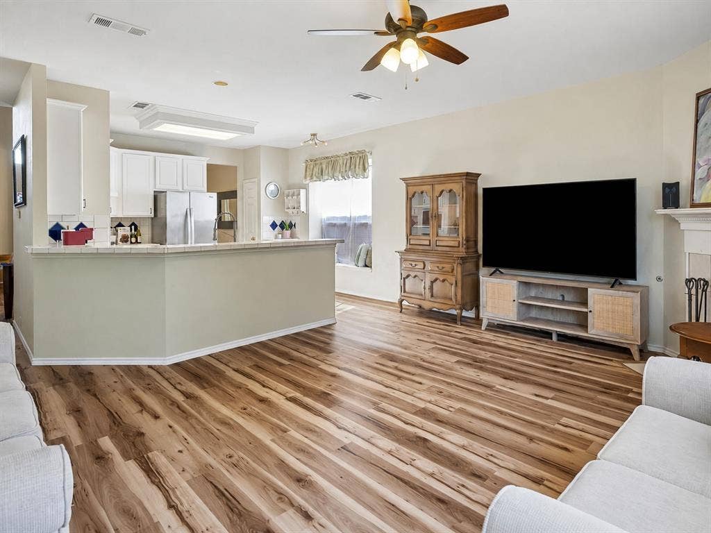 11379 Lockshire Drive, Frisco, TX 75035 Open-concept living area with wood-finish flooring, a ceiling fan, and white kitchen cabinetry