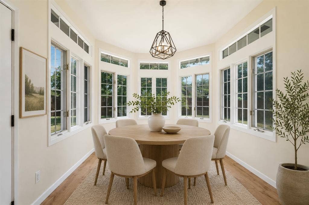 Bay window design featuring multiple transom windows, wood-finish flooring, and a contemporary light fixture (Virtually staged)