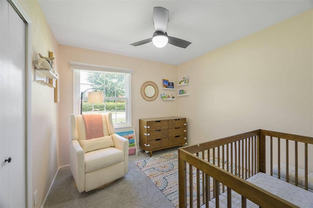 Bright room featuring neutral-toned walls, a window with exterior tree-line visibility, and a ceiling fan with integrated lighting