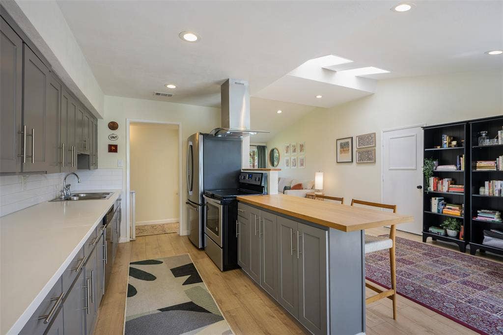 Kitchen with gray cabinetry, white countertops, and a wood-finish island