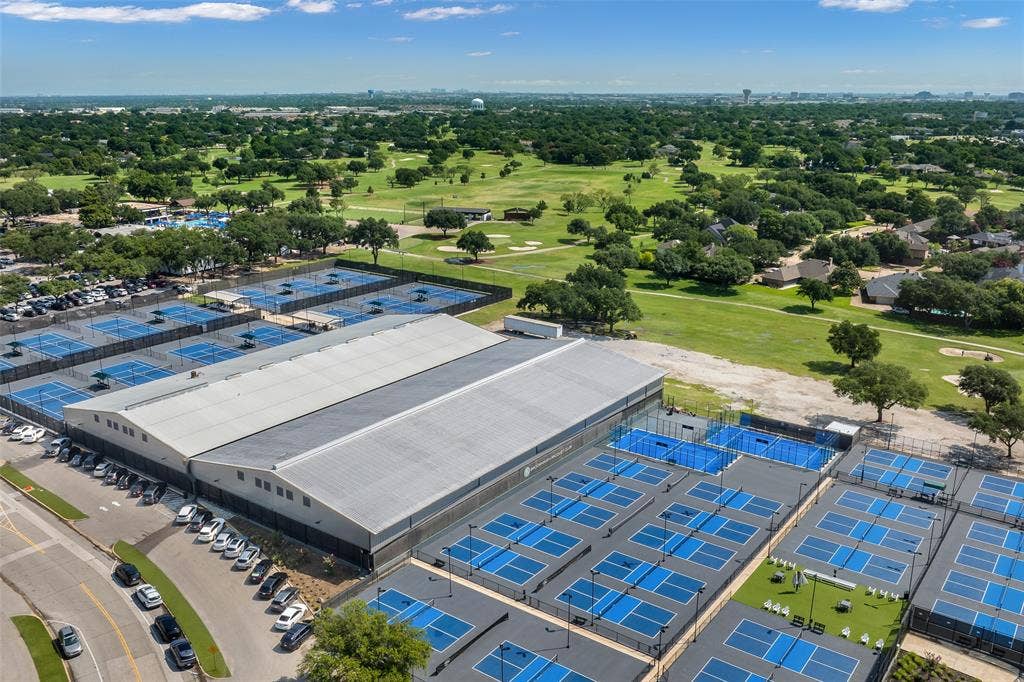 Extensive athletic facility featuring multiple outdoor courts, an indoor court structure, and ample parking