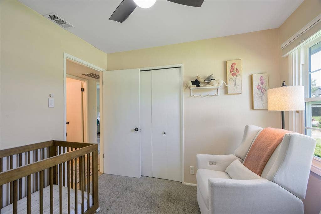 Carpeted room featuring a ceiling fan, window with blinds, and white bi-fold closet doors