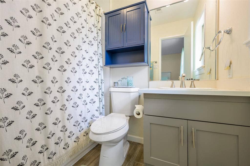 Bathroom featuring a vanity with a light gray shaker-style cabinet, a white countertop, and a rectangular undermount sink