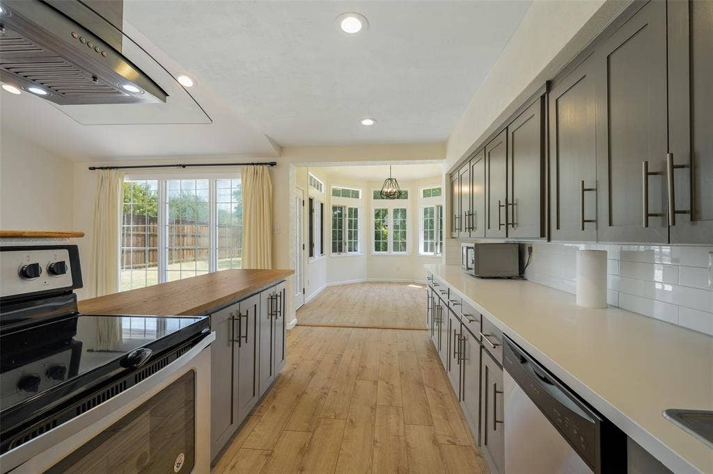 Kitchen featuring a wood-finish island countertop, recessed lighting, stainless steel range hood, light-toned wood-finish flooring, and a subway tile backsplash