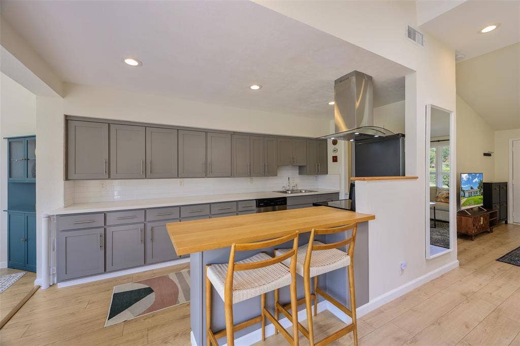 Contemporary kitchen featuring extensive gray cabinetry, light countertops, and a subway tile backsplash
