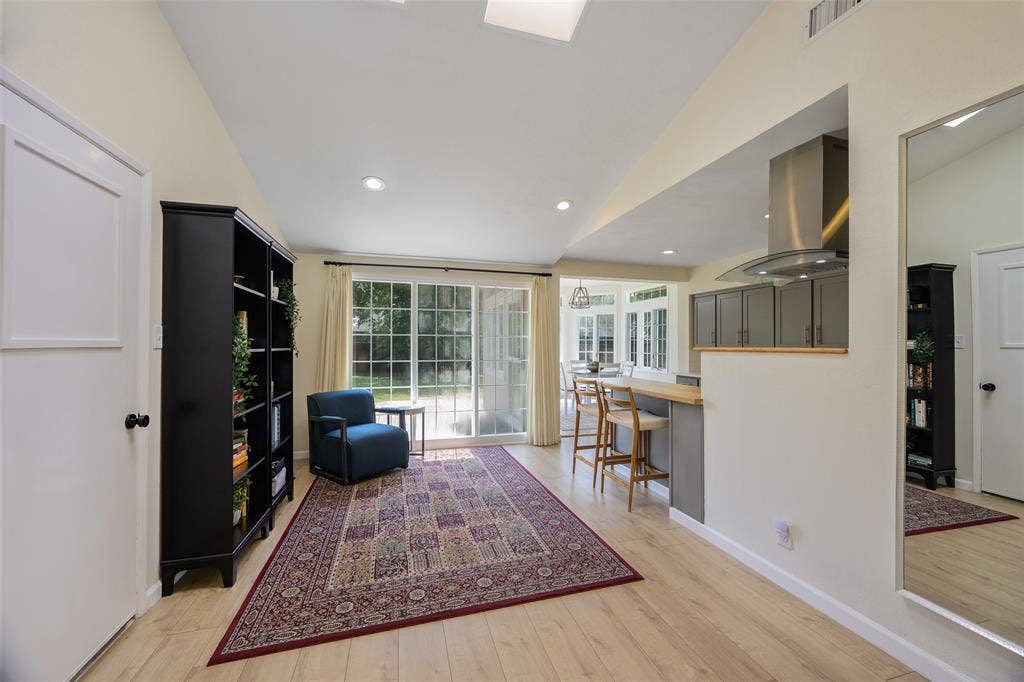 Spacious room with wood-finish flooring, vaulted ceiling, and recessed lighting