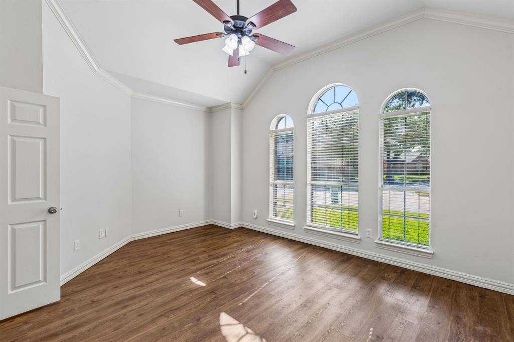 6852 High Field Trail, Plano, TX 75023 Bright and spacious room showcasing soaring vaulted ceilings, rich wood-finish flooring, and three sets of French doors with arched transom windows flooding the space with natural light