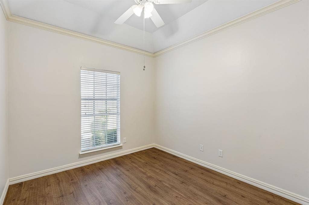 6852 High Field Trail, Plano, TX 75023 Spacious room featuring wood-finish flooring, a ceiling fan, crown molding, and neutral wall tones