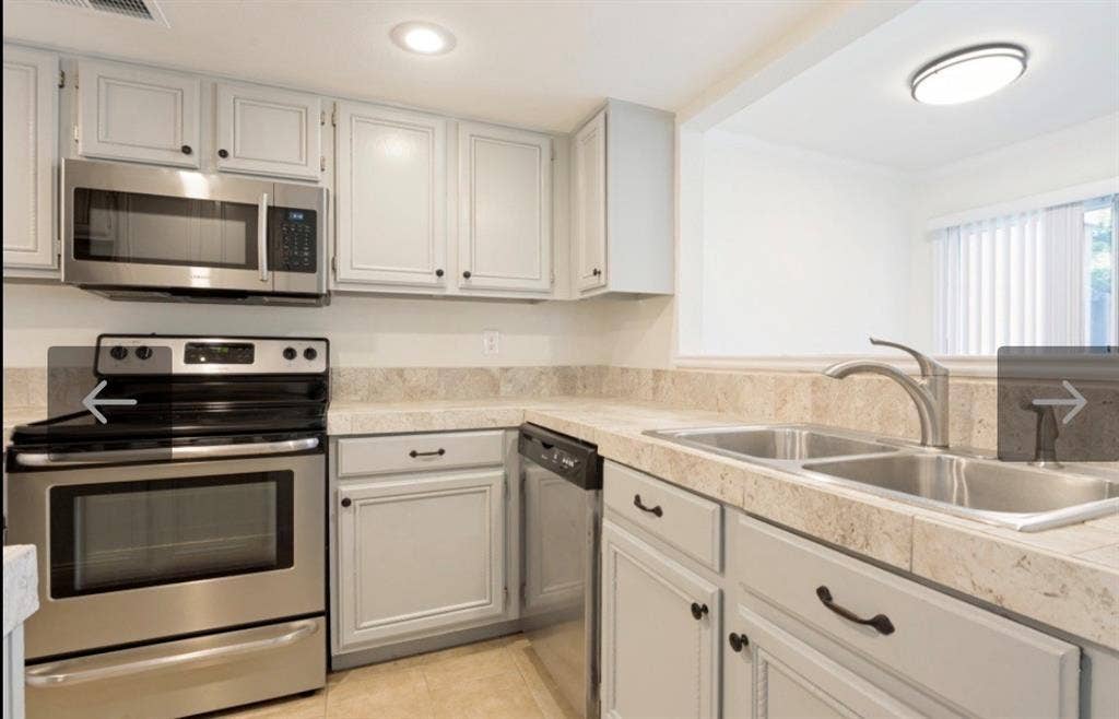 8400 Hickory Street, #1504, Frisco, TX 75034 Kitchen featuring light-colored cabinetry with dark hardware, stainless steel appliances, a dual basin sink with a chrome faucet, and patterned countertops with a matching backsplash