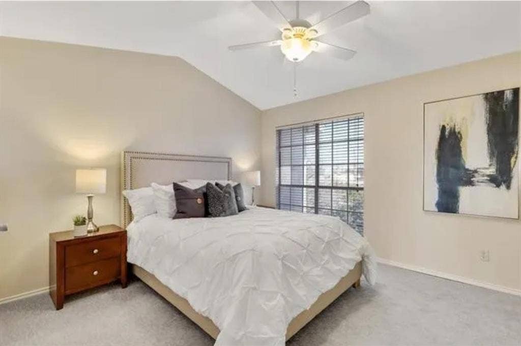 8400 Hickory Street, #1504, Frisco, TX 75034 Vaulted ceiling bedroom featuring light beige walls, a neutral carpet, a large window with horizontal blinds, and a ceiling fan with integrated lighting