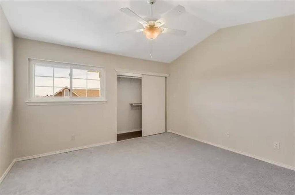 8400 Hickory Street, #1504, Frisco, TX 75034 Vaulted ceiling bedroom featuring light gray carpeting, a built-in closet with sliding doors, a white ceiling fan with integrated lighting, and a white-framed window