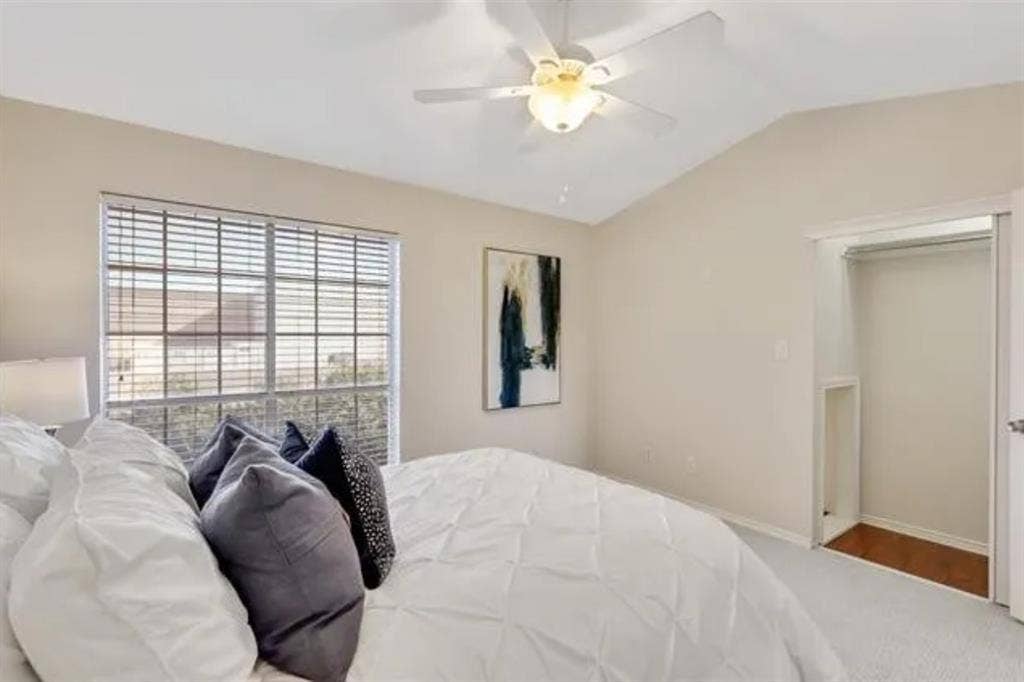 8400 Hickory Street, #1504, Frisco, TX 75034 Room featuring a vaulted ceiling with a ceiling fan, a large window with blinds, and a built-in closet with wood-finish flooring